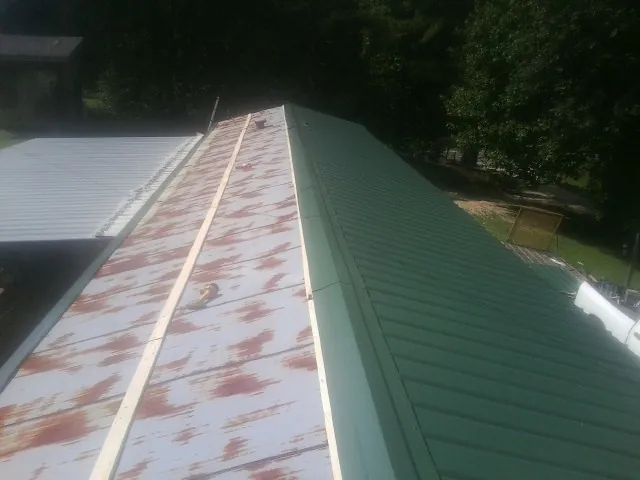 Old rusted panels beside newly installed green metal roofing — Wind Damage Roof Repair by Roofing Brothers in Galivants Ferry