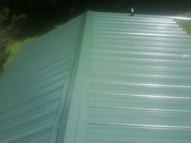 New green metal panels meeting at the ridge of a roof in Galivants Ferry
