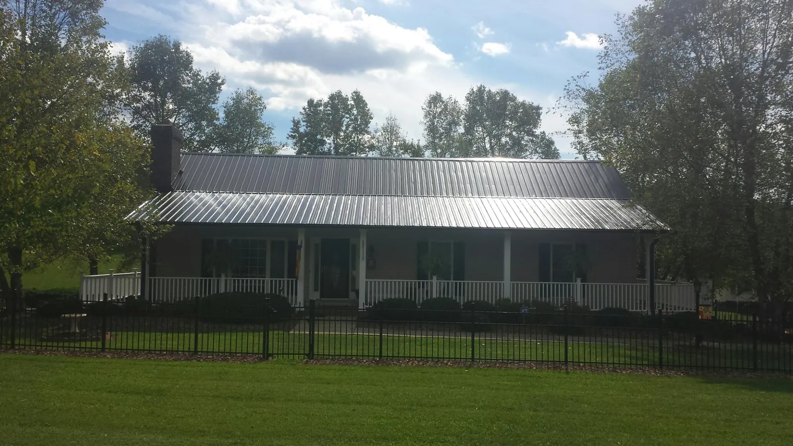 Gray metal roof on a brick ranch with a full width front porch — Gutter Guard Installation work by our crew in Galivants Ferry