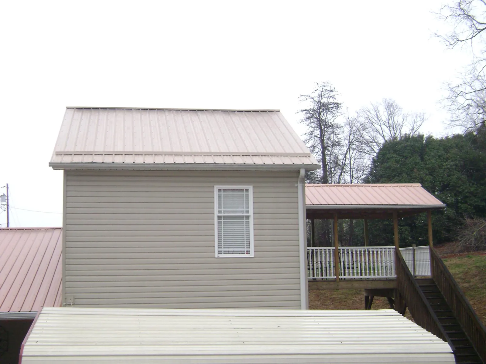 Tan metal roofs on a two story addition and attached porch, from a Roof Replacement job in Galivants Ferry
