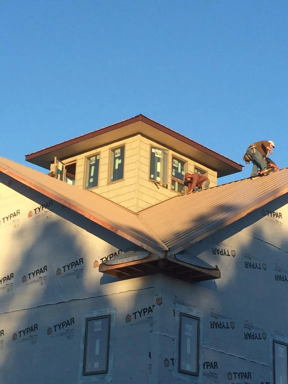 Roofers working around a rooftop cupola on a new metal roof at sunset — Roof Waterproofing in Galivants Ferry by Roofing Brothers